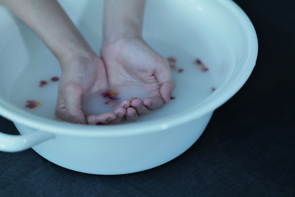 ハーブの入った琺瑯の容器。手浴しているところ