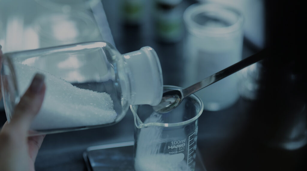 ガラス瓶からガラスのビーカーに粉を入れている様子