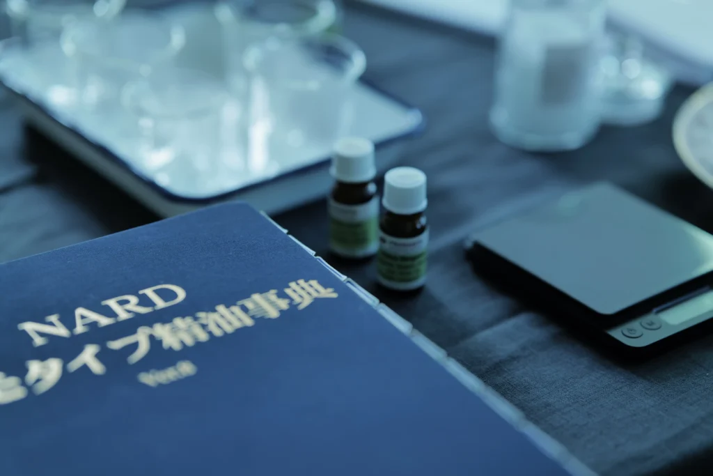 机の上に精油辞典と精油、たくさんのビーカー、スケールなど