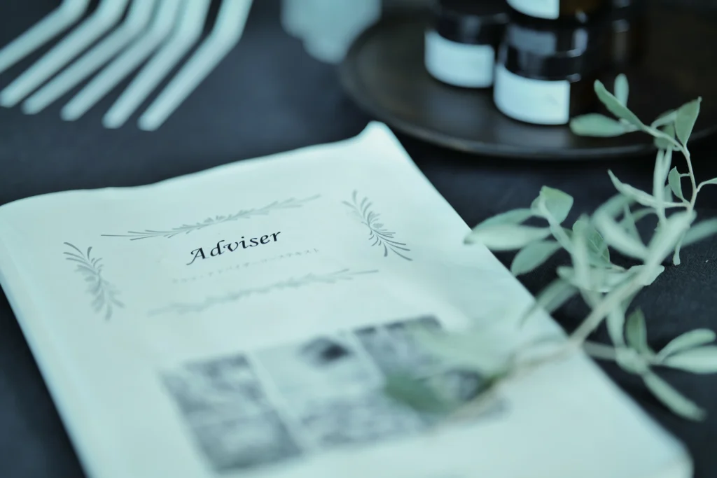 机の上にAdviserのテキストやガラスの器、ムエットなど