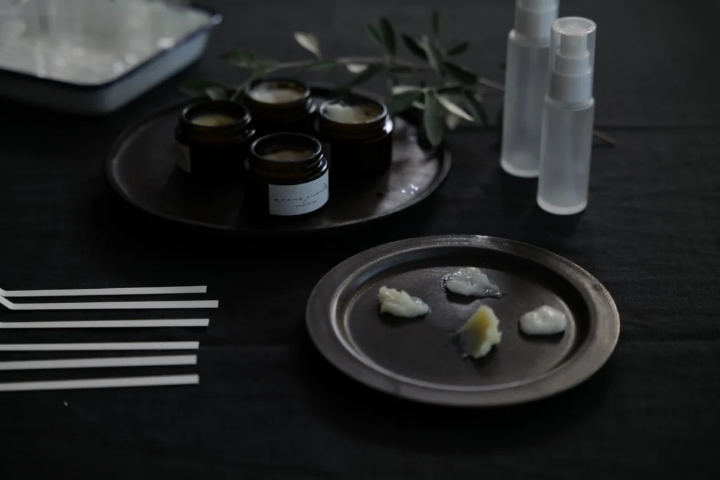 机の上にムエット、ガラスの容器、スプレーボトル。お皿の上にはシアバターがのっている様子